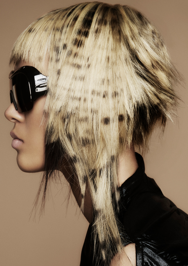Foto der Avantgarde Kollektion "Luminary" von Bernadette Beswick. Weibliches Model mit schwarzem Lederblazer & Sonnenbrille und einem futuristischen blonden Kurzhaarschnitt