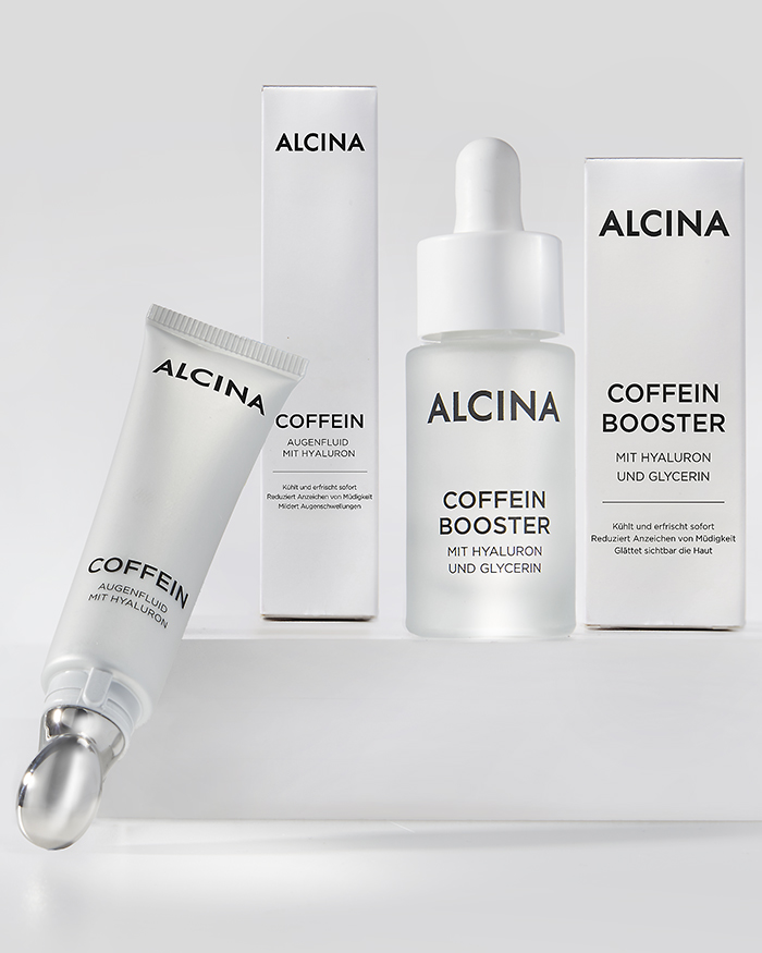 Bild der Produktserie ‚ALCINA Koffein Booster‘: Mehrere Augenpflegeprodukte nebeneinander arrangiert, mit Fokus auf das moderne, minimalistische Verpackungsdesign